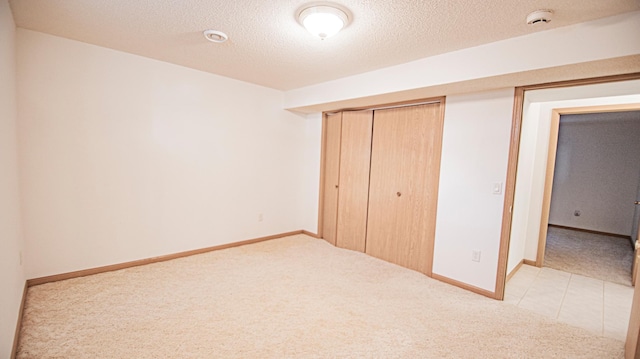 unfurnished bedroom with light carpet, a closet, and a textured ceiling