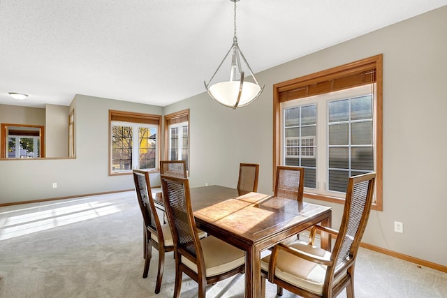 dining area featuring light colored carpet and a textured ceiling