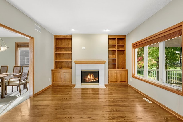 unfurnished living room with a tile fireplace and light hardwood / wood-style flooring