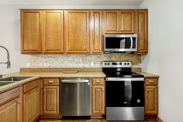 kitchen with decorative backsplash, sink, stainless steel appliances, and a textured ceiling