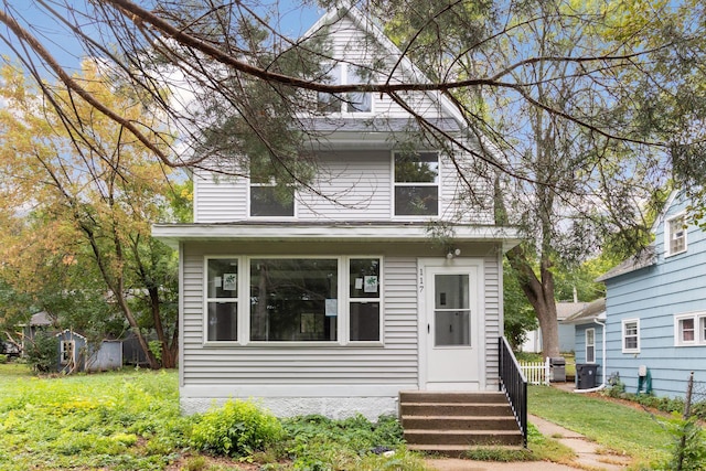 view of front of home with a front lawn and a storage shed