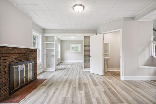 unfurnished living room featuring light wood-style flooring, a fireplace, and baseboards