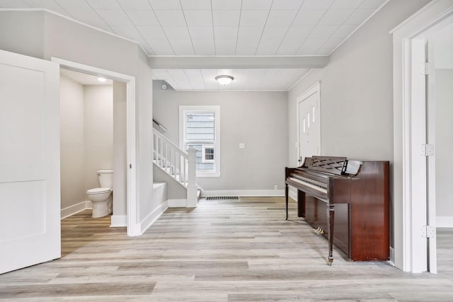 entryway with light wood-style flooring, beamed ceiling, stairway, and baseboards