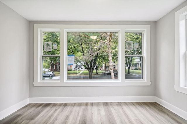 empty room with plenty of natural light, light wood-style flooring, and baseboards