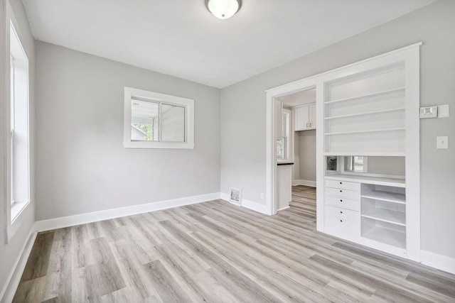 unfurnished bedroom with visible vents, baseboards, light wood-style floors, a closet, and a walk in closet