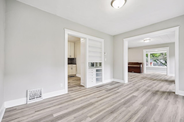 spare room featuring light wood-type flooring, visible vents, and baseboards