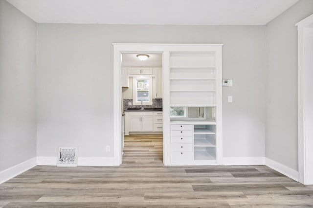 spare room featuring light wood-type flooring, visible vents, and baseboards