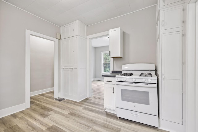 kitchen featuring visible vents, light wood-style flooring, white cabinets, white range with gas cooktop, and baseboards