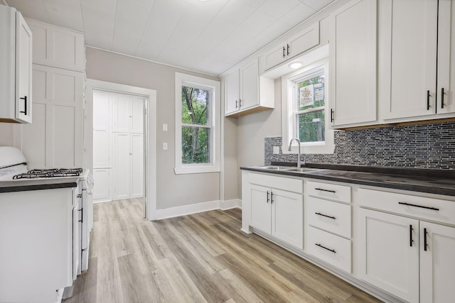 kitchen with dark countertops, a wealth of natural light, white gas range, and a sink