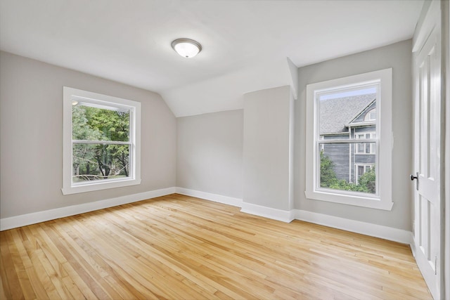 bonus room with lofted ceiling, baseboards, and light wood finished floors