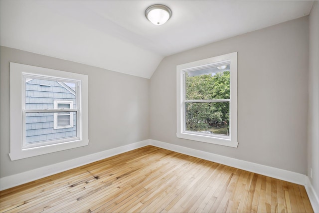 additional living space featuring vaulted ceiling, light wood-type flooring, and baseboards