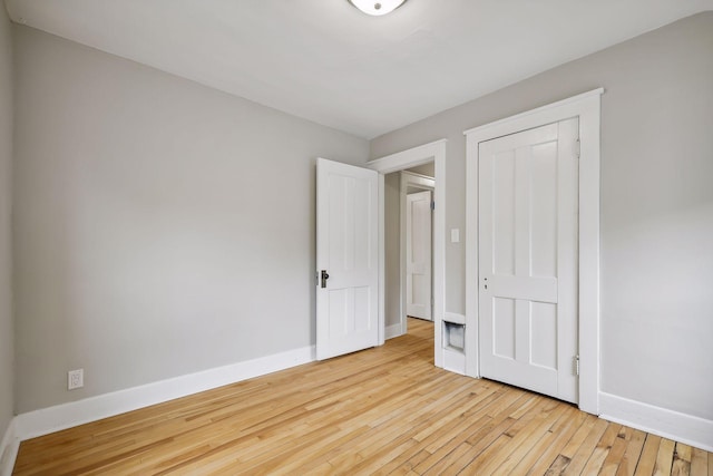 unfurnished bedroom featuring a closet, baseboards, and hardwood / wood-style floors