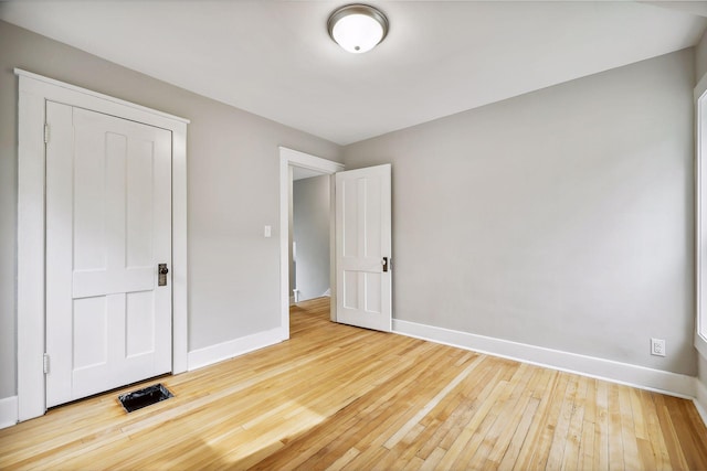 unfurnished bedroom featuring hardwood / wood-style floors, visible vents, and baseboards