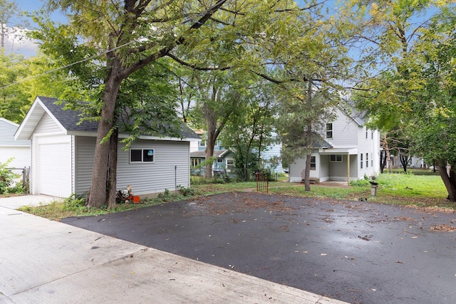 view of front of property featuring a garage, roof with shingles, fence, and an outbuilding