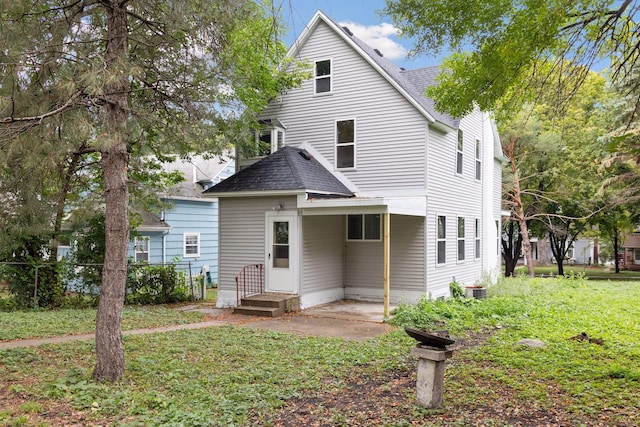 rear view of property featuring a yard, roof with shingles, and fence