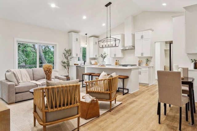 living room featuring light wood-type flooring, an inviting chandelier, lofted ceiling, and sink