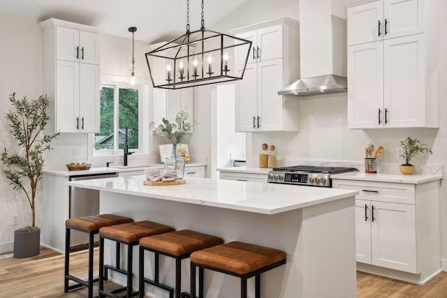 kitchen featuring white cabinets, stainless steel appliances, light hardwood / wood-style flooring, and wall chimney exhaust hood