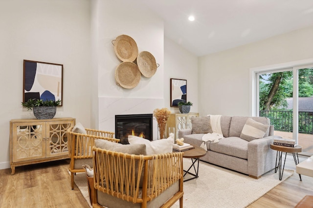 living room with light hardwood / wood-style floors, a premium fireplace, and vaulted ceiling