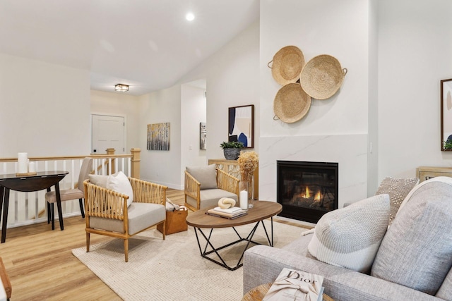 sitting room with a premium fireplace, light hardwood / wood-style floors, and lofted ceiling