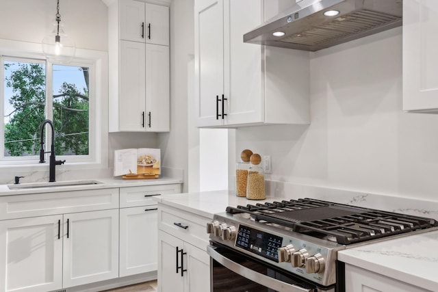 kitchen with white cabinets, stainless steel range with gas cooktop, sink, wall chimney range hood, and light stone countertops