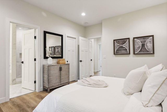 bedroom featuring light wood-type flooring and ensuite bath