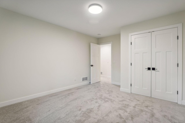 unfurnished bedroom featuring a closet and light colored carpet