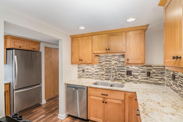 kitchen with sink, decorative backsplash, light stone countertops, appliances with stainless steel finishes, and dark hardwood / wood-style flooring