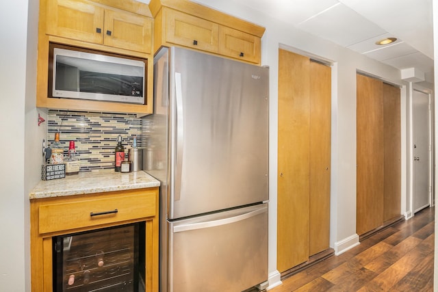 kitchen with decorative backsplash, light stone counters, appliances with stainless steel finishes, dark hardwood / wood-style flooring, and beverage cooler