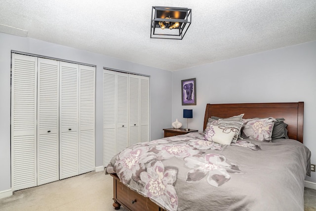 carpeted bedroom featuring multiple closets and a textured ceiling