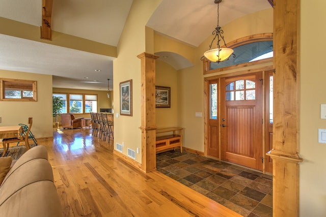 foyer entrance with dark hardwood / wood-style flooring, high vaulted ceiling, and decorative columns