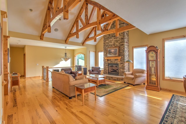 living room featuring beamed ceiling, a stone fireplace, high vaulted ceiling, and light hardwood / wood-style flooring