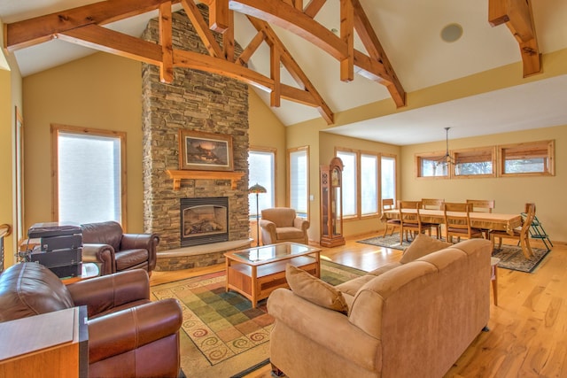 living room with a stone fireplace, light hardwood / wood-style flooring, high vaulted ceiling, and beamed ceiling