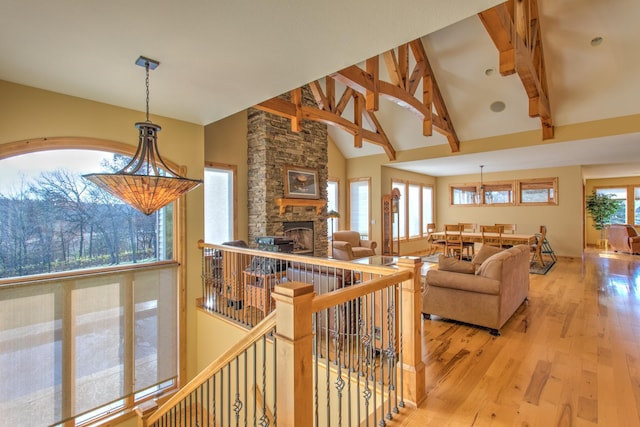 living room featuring a fireplace, beam ceiling, high vaulted ceiling, and light hardwood / wood-style flooring