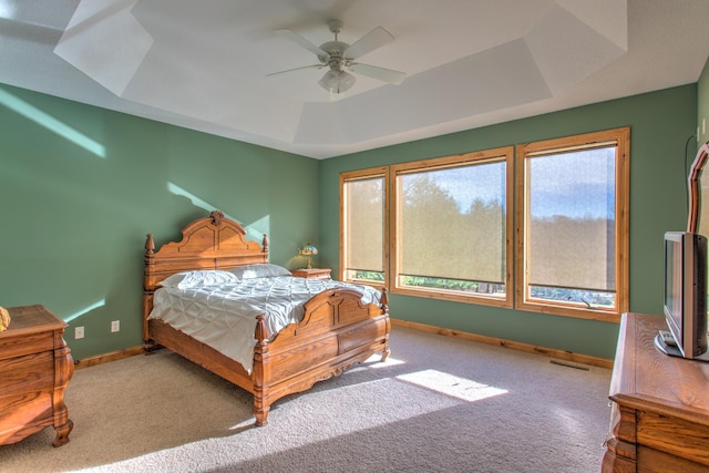 carpeted bedroom featuring a tray ceiling and ceiling fan