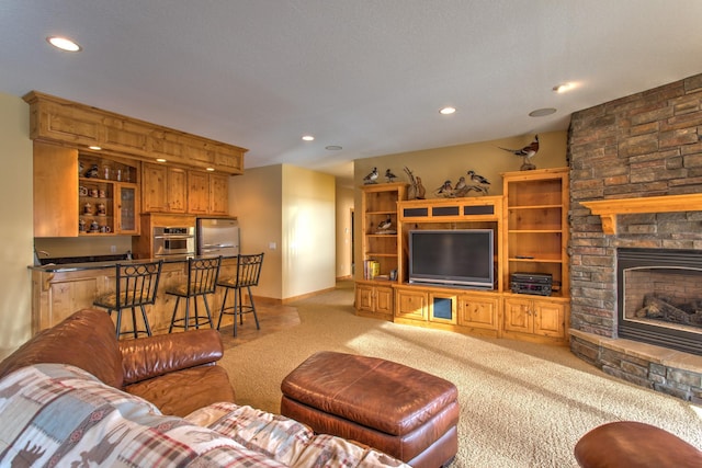 living room featuring a stone fireplace, light carpet, and indoor bar