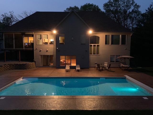 back house at dusk featuring a patio area and a sunroom