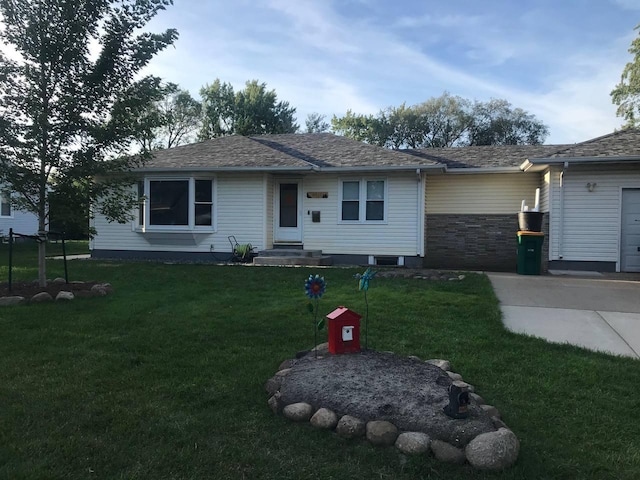 ranch-style home featuring an attached garage, concrete driveway, a front lawn, and a shingled roof