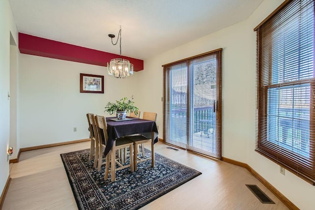 dining room with a healthy amount of sunlight, an inviting chandelier, and light hardwood / wood-style flooring