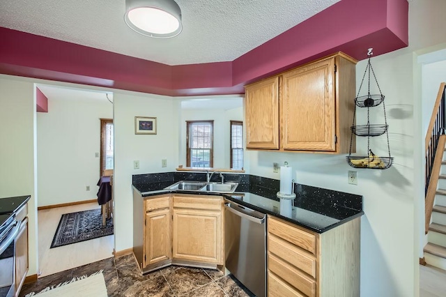 kitchen featuring light brown cabinetry, dishwasher, sink, and a textured ceiling