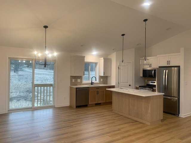 kitchen with light wood finished floors, a sink, stainless steel appliances, light countertops, and a chandelier
