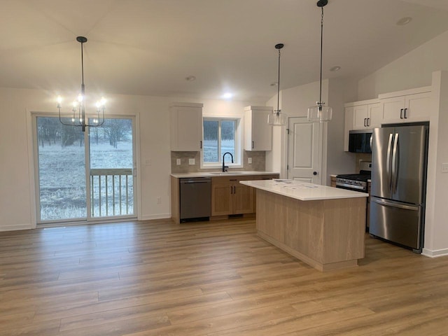 kitchen featuring light wood finished floors, light countertops, decorative backsplash, appliances with stainless steel finishes, and a sink