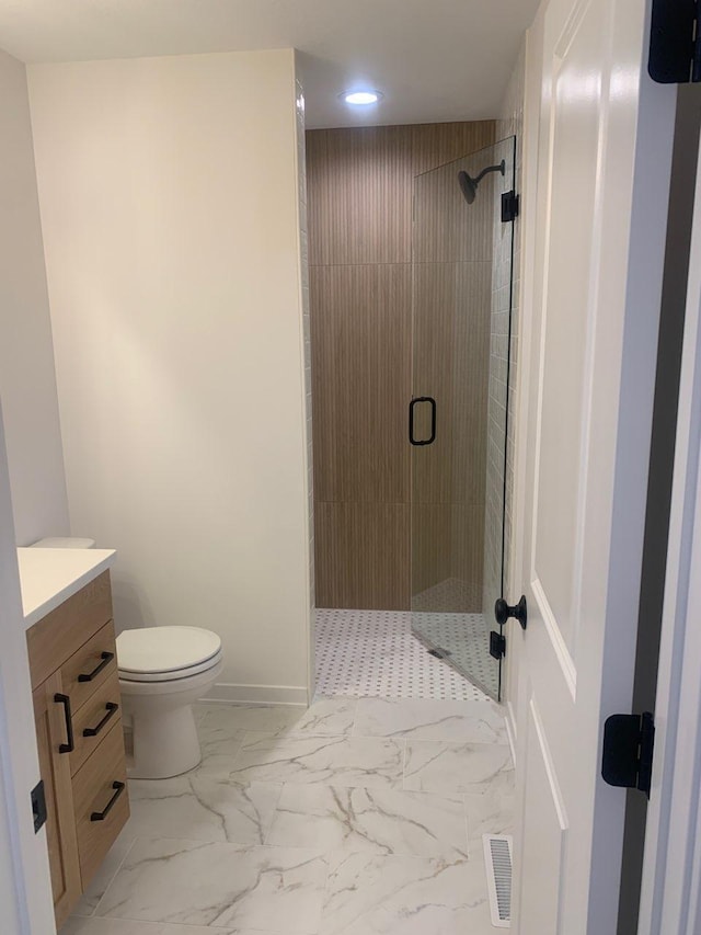 bathroom with vanity, toilet, marble finish floor, and a stall shower