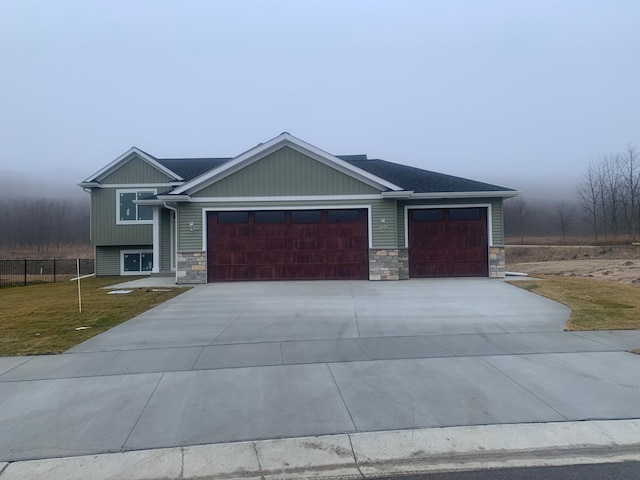 craftsman-style home with fence, concrete driveway, a front yard, a garage, and stone siding