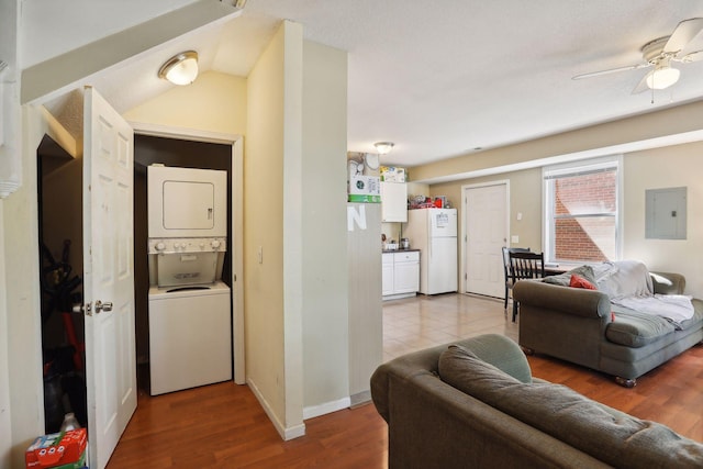 living room with hardwood / wood-style floors, stacked washer / drying machine, ceiling fan, and lofted ceiling