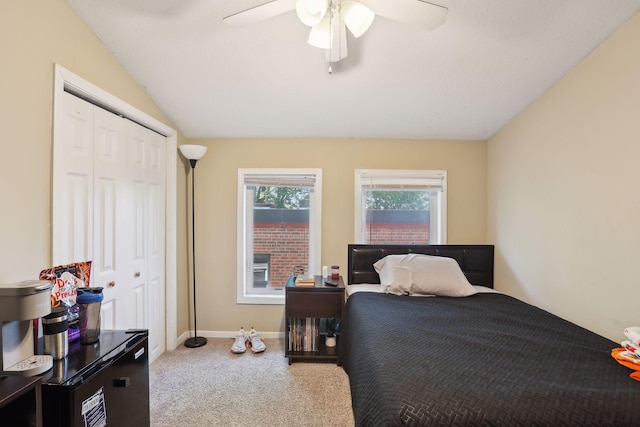 carpeted bedroom with ceiling fan, lofted ceiling, and a closet