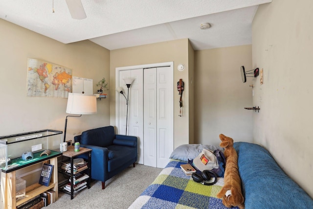 bedroom featuring ceiling fan, light colored carpet, a textured ceiling, and a closet