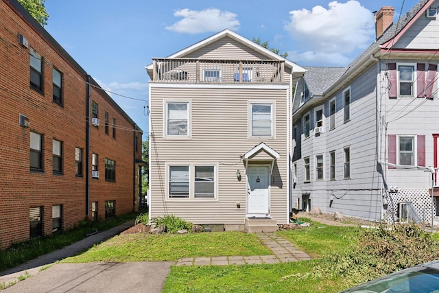 front facade featuring a balcony and a front yard