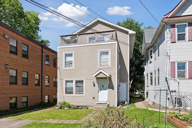 view of front of house with a balcony and a front lawn