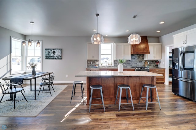 kitchen with a kitchen island, decorative light fixtures, white cabinetry, sink, and stainless steel fridge with ice dispenser