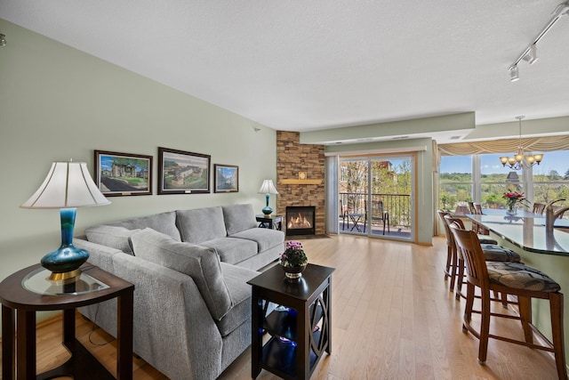630 Main St N Unit 202, Stillwater, MN 55082 - living room with a chandelier, light wood finished floors, a stone fireplace, and track lighting